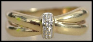 A hallmarked 9ct gold and diamond crossover band ring set with 2 illusion set diamonds.