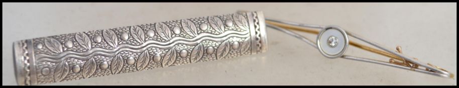 An 18t Art Deco bar brooch with central diamond on roundel mount with pin verso. Together with a