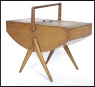 A retro 1960s Danish teak wood sewing box having opening cantilever sections raised on twin