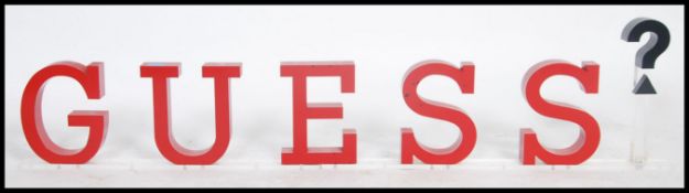 A group of red plastic advertising / point of sale letters forming the word Guess? mounted on a
