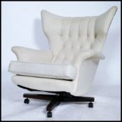 A good 1970's retro large oversized batwing swivel armchair being raised on a 4 point swivel base