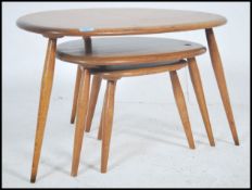 An Ercol beech and elm retro pebble nest of tables, shape 354. Each raised on turned legs having