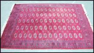 A vintage 20th century Afghan carpet rug of woollen construction having red ground with geometric