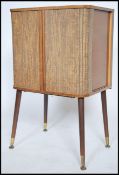 A 1950's faux wood formica tv - entertainment cabinet being raised on dansette legs, the cabinet