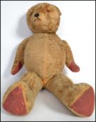An early 20th century large straw filled teddy bear of large form with articulated arms and legs