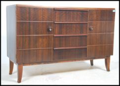 A vintage 20th century teak wood sideboard having a series of beehive drawers and cupboards raised