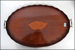 An Edwardian mahogany inlaid oval butlers tray a scalloped gallery edge, twin handles with conch
