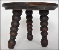 An unusual early 20th century oak milking stool with turned bobbin legs