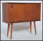 A retro 20th century teak wood cupboard, having a pair of sliding doors with recessed circular