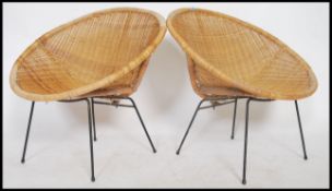 A pair of mid century rattan weave ' tropics ' chairs. Each of tub form being raised on ebonised