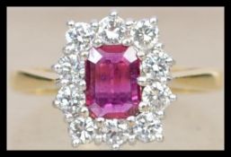 A hallmarked 18ct gold diamond and red stone ring set with a central emerald cut red stone