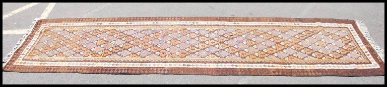 A large Afghan / Persian Kilim runner having central run of diamond lozenge medallions within
