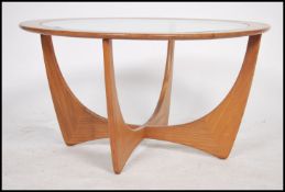 A 1970's retro Atomic teak wood coffee table of round form with inset glass table top. All raised on