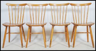 A set of 4 Ercol style retro dining chairs and saddle seats being raised on turned legs with