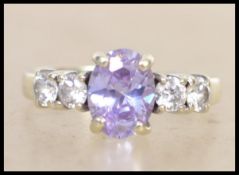 A hallmarked 9ct gold ring set with an oval cut purple stone flanked by four round cut CZ.