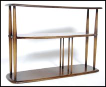 An Ercol beech and elm wood bookcase having 3 shelves united by spindle gallery uprights.Each tier