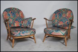 A pair of Ercol beech and elm blond wood Windsor pattern armchairs raised on turned legs with
