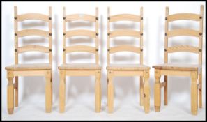A set of 4 contemporary pine dining chairs having high backs over panel seats and raised on