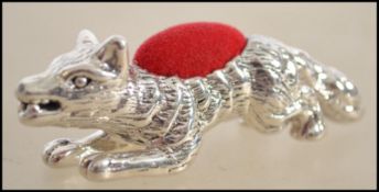 A silver pin cushion in the form of a fox having a