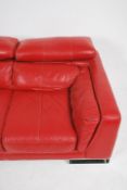 A contemporary red leather Italian sofa raised on