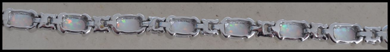 A beautiful ladies silver and opal adorned tennis