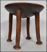 An believed 19th century African hardwood stool having a dished seat being raised raised on