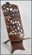 A 20th century African tribal Congo birthing chair of two part construction having a panel seat with