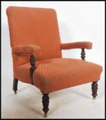A Victorian library armchair raised on turned legs and brass castors upholstered in damask velour