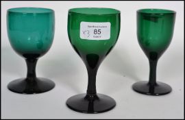 A group of three Georgian 18th century Bristol green glass wine glasses raised on a plain foot and