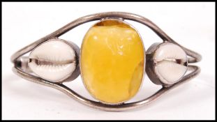 A sterling silver bangle bracelet of rigid form with large central amber cabochon with adjacent
