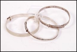 A group of three silver chase decorated christening bracelets, one being hallmarked and dating to