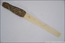 A 19th century Japanese bronze and bone page turner, having a cast bronze handle depicting a
