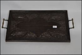 A Jacobean style ebonised oak hand carved butler's tray with brass scrolled handles.