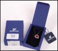 A boxed ( appears unused ) Swarovski silver and garnet stone heart shaped pendant with a halo of