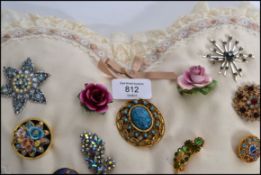 A heart shaped pad / cushion adorned with several vintage and retro costume jewellery brooches of