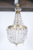 A large early 20th century Empire style brass drop chandelier having multiple faceted crystal