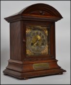 An oak mantel clock having dome top with a bevelled bezel and a silvered and gilt face, the clock is