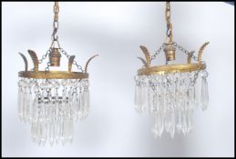 A pair of early 20th century Empire brass drop chandeliers having multiple faceted crystal drops.