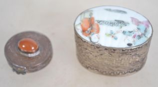 A 20th century Chinese white silvered metal pill pot having a painted scene together with another.