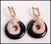 A pair of silver gilt and onyx ladies earrings in the form of panthers, each with emerald eyes.