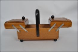 A vintage retro 20th century metamorphic sewing work box with an ebonised handle atop.