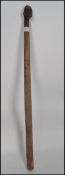 An African tribal ceremonial staff constructed from a singular piece of wood having a carved mask to