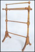 A Victorian style beech wood towel rail with out swept legs, turned rails and finials tops