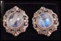 A good pair of ladies silver and moonstone earrings having a rococo style halo to each.  Complete in