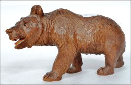 An early 20th century large carved Black Forest bear standing on all four legs, set with glass