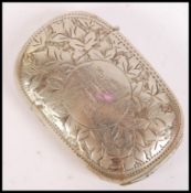 A silver white metal vesta case of oval form with chased decoration and monogram to front.