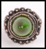 A fabulous asiatic silver white metal ladies ring with green conical protruding stone set over a