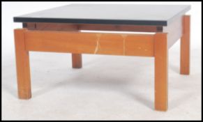 A 1970's Danish influence retro teak and black acrylic top coffee table of square form being