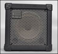 A vintage Roland Cube 15 black guitar amp having a