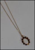 A 9ct gold and and red stone pendant and necklace combination. The oval cut opal surrounded by